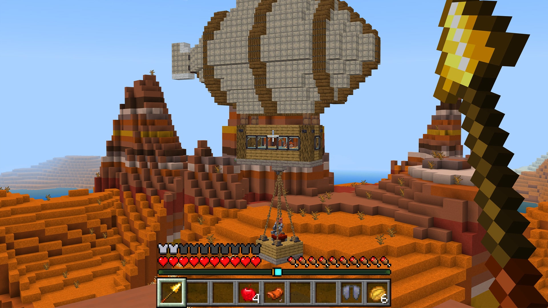 An airship over the badlands with a hanging basket