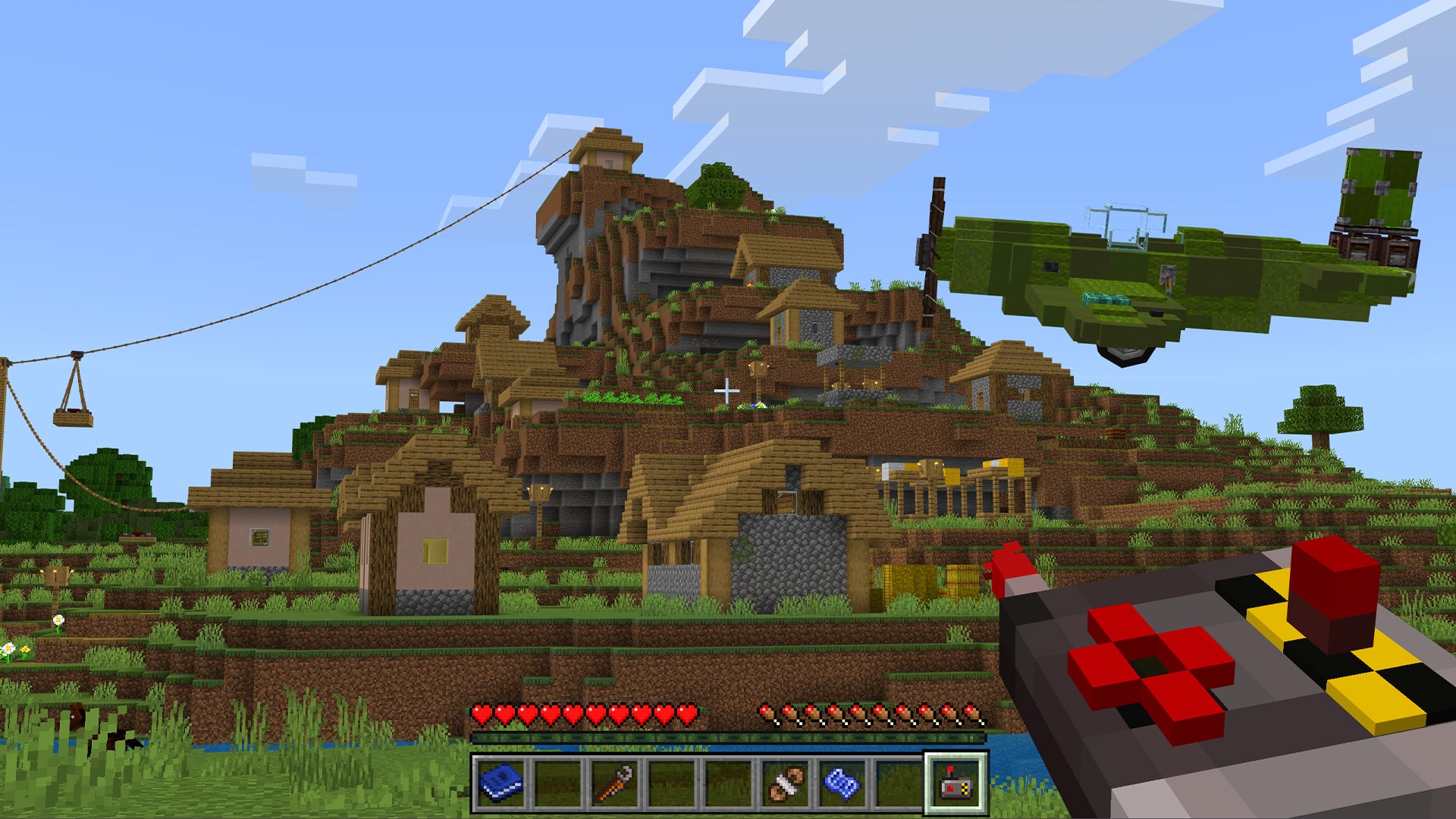 A cable car over a village, with a plane overhead